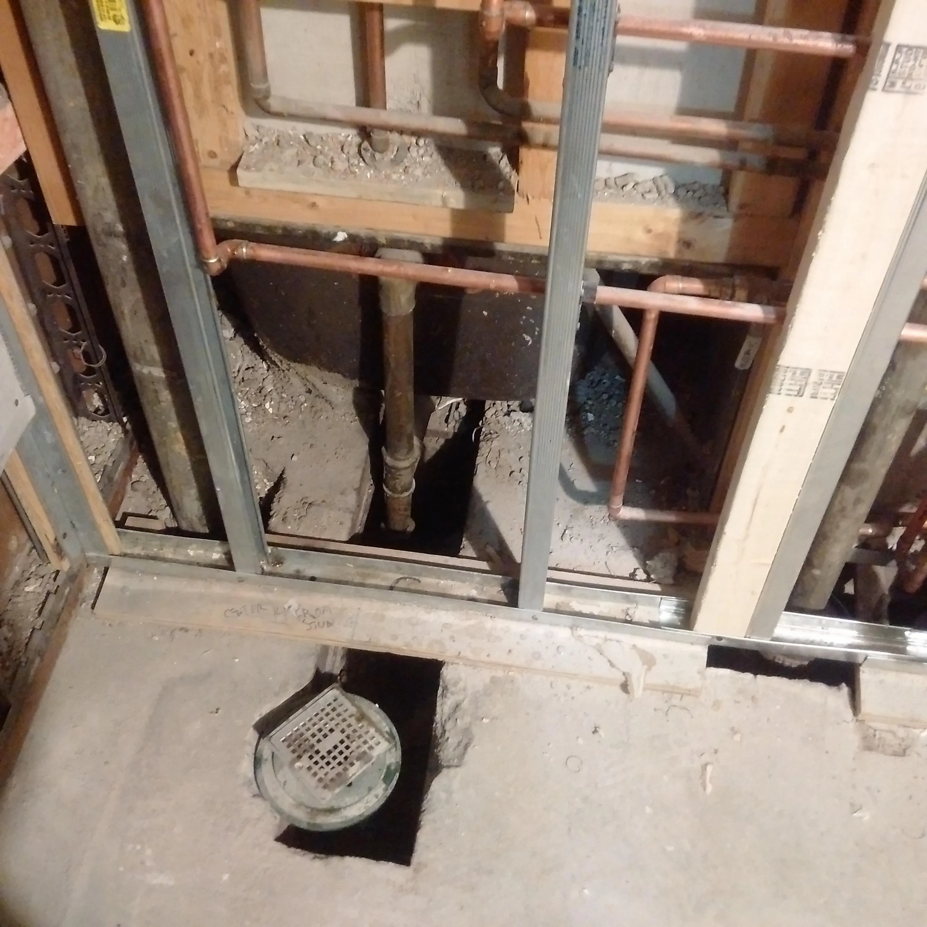 Bathroom rough-in plumbing with copper piping and floor drain installation